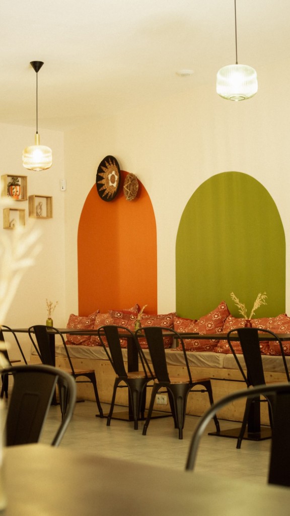 Intérieur du café Nayou — arches terracotta et verte, coussins aux motifs ethniques